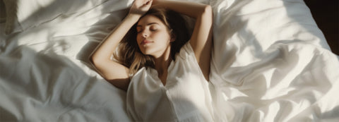 junge frau mit langen haaren und weißem kleid liegt auf weißer bettdecke in der sonne