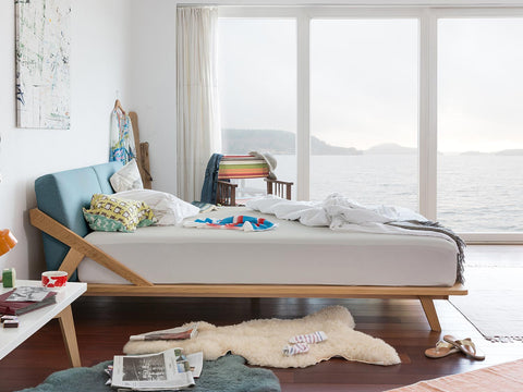bett aus eiche massivholz mit blauem rückenpolster in einem schlafzimmer mit blick auf einen see #160-B-180-B-200-B
