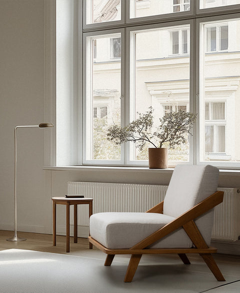 nordic sapce sessel mit gestell aus eiche massivholz geölt und polstern in der farbe natur in berliner altbauwohung teppich tischleuchtee und pflanze auf fensterbank