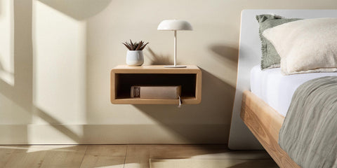private space bett und nachttisch aus esche massivholz und weiß lackiertem rückenteil kissen und graue bettdecke auf matratze in schlafzimmer mit sonne