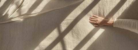 hand streicht über weiche decke in der sonne mit schatten von fenstersprossen