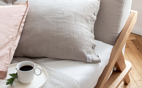 designdetail von nordic space bett mit bettgestell aus eiche massivholz polster kissen in der farbe natur und kaffeetasse auf tablett