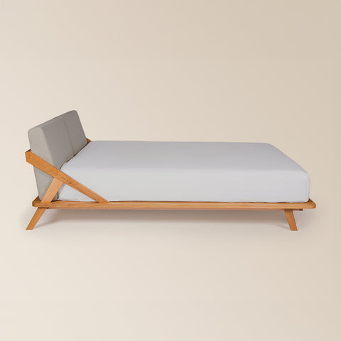 seitenansicht nordic space bett aus eiche massivholz mit rückenpolster bezogen mit möbelstoff in der farbe warmgrau für matratzengröße 160 x 200 cm